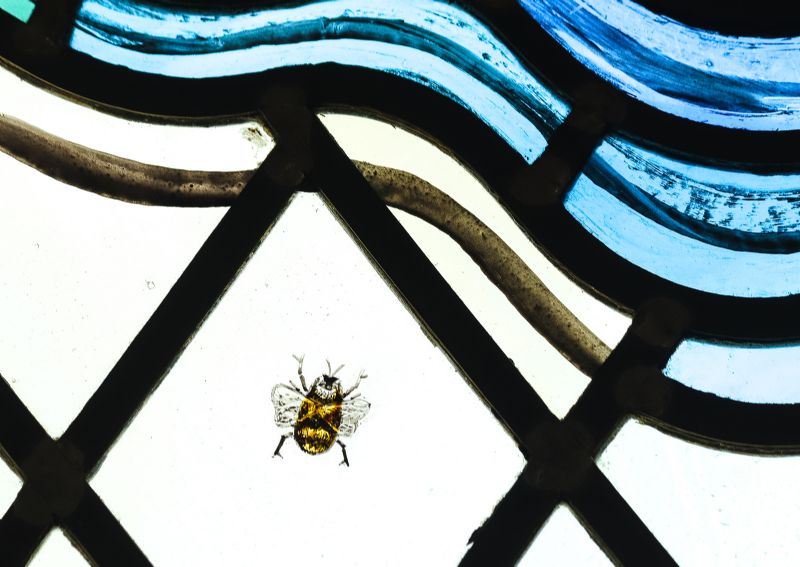 A detailed bee depiction in the stained glass of the Kirk